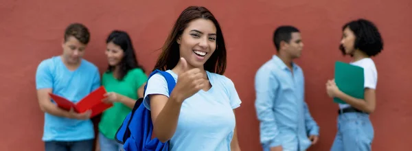幸せなメキシコの女性学生は夏に屋外で多民族の学生のグループと親指を表示します — ストック写真