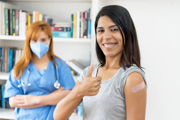 第三次接种Covid 19疫苗后 与护士一起在疫苗接种中心快乐的拉丁裔美国妇女 — 图库照片