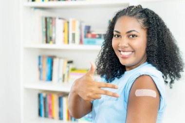 Üçüncü aşıdan sonra Omikron varyantlarına karşı korunmak için Covid 19 'a gülen Latin Amerikalı genç yetişkin kadın.