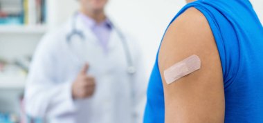 Coronavirus 'a karşı korunmak için Covid 19' a yapılan üçüncü aşıdan sonra kolunda alçı, başparmağında da doktor.