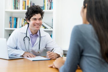 Kadın hastalarla hastanedeki iyi haberler hakkında konuşan gülen bir doktor.