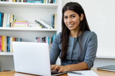 Ofiste bilgisayar başında çalışan Güney Amerikalı bir kadın.