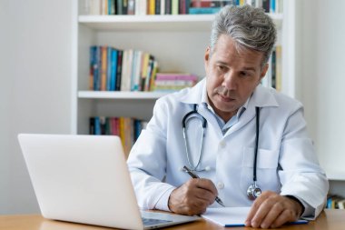 Onkolojist kanser hakkında kitaplar okuyor ve hastanenin bilgisayarında çalışıyor.