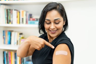 Hastanede aşılandıktan sonra alçıyla gülen Latin Amerikalı olgun bir kadın.