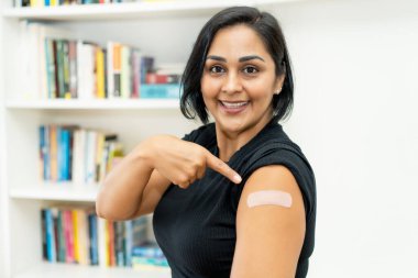 Hastanede aşılandıktan sonra alçılı Latin Amerikalı olgun kadın