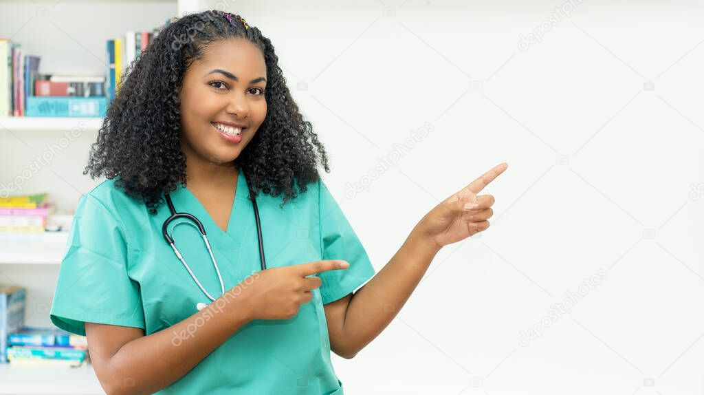 Latin american medical student or female nurse pointing sideways at clinic