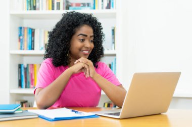 Brezilyalı genç yetişkin evde bilgisayar başında film izliyor.