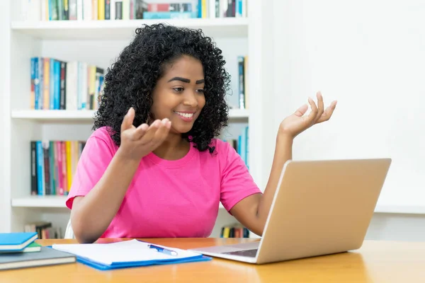 オンラインレクチャー ブラジルの若い大人の女性が自宅で机の中で学生と議論中 — ストック写真