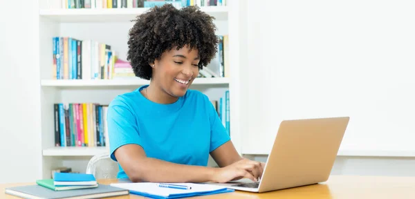 楽しい笑いアフリカ系アメリカ人女性若い大人ショッピングオンラインでコンピュータに机の上にホーム — ストック写真
