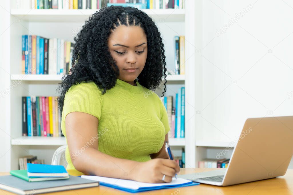 Corpulent african american female student preparing for graduation indoors at home