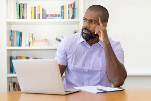成熟的非洲裔美国商人在办公室的办公桌前电脑上思考着一个问题 — 图库照片