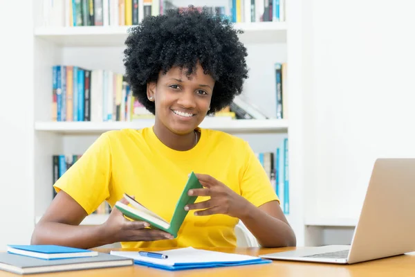 Rindo Afro Americana Estudante Com Livro Dentro Casa Mesa — Fotografia de Stock