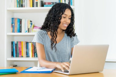 Güney Amerikalı kız öğrencilerin üniversitenin masasında bilgisayar öğrenmesine gülüyordu.