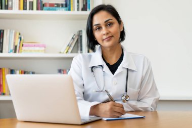 Güzel Latin Amerikalı olgun doktor hastanedeki ofiste çalışıyor.