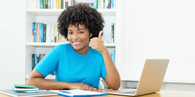 Happy african american female student learning at computer indoors at desk at home