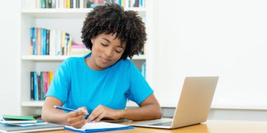 African american female student learning foreign language indoors at desk at home