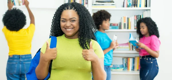 在图书馆里 快乐的非洲裔美国女学生和一群大学生竖起大拇指 — 图库照片