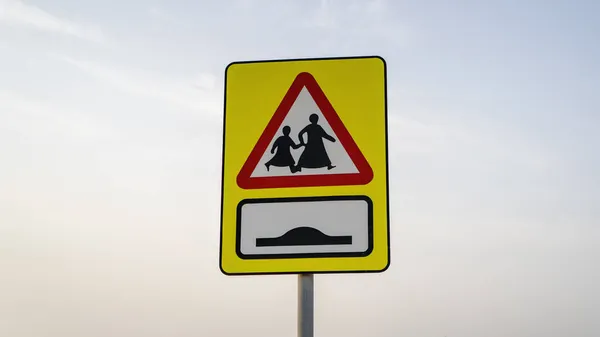 School children crossing sign in qatar along with speed bump sign on the road