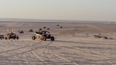 Doha, Katar - 11 Mart 2022: İnsanlar Sealine 'deki kum tepelerinde dörtlü bisiklet sürüyor.