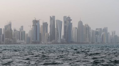 Qatar skyline with rough sea in the foreground on a windy and rainy day.