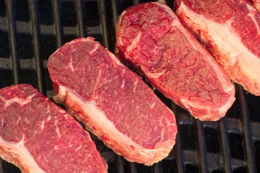 Gaz ızgarasında çiğ biftek pişirip seçici bir odak noktasıyla vuruyorlar.