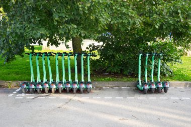 Electric scooters station in European city. Electric transport rent. Electric scooters parked at the street. Urban vehicle mobility concept.
