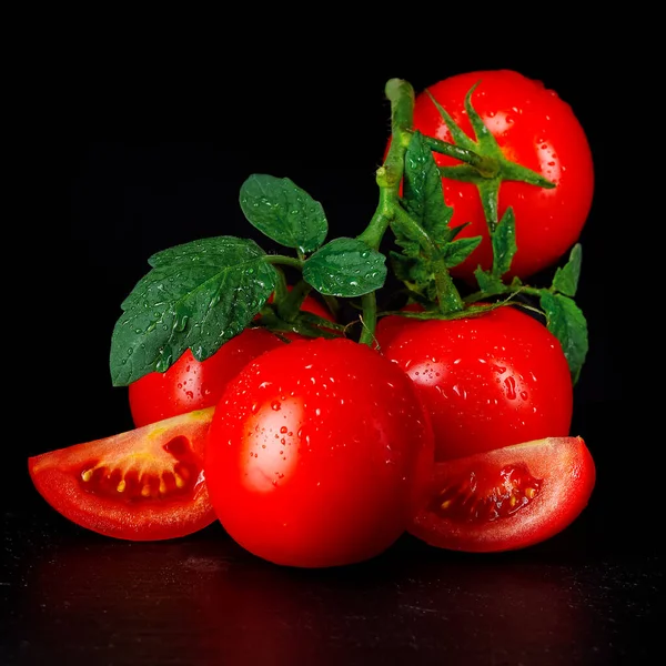 Reife Bio-Tomaten auf dem schwarzen Tisch mit Wassertropfen — Stockfoto