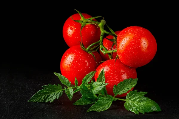 Reife Bio-Tomaten auf dem schwarzen Tisch mit Wassertropfen — Stockfoto