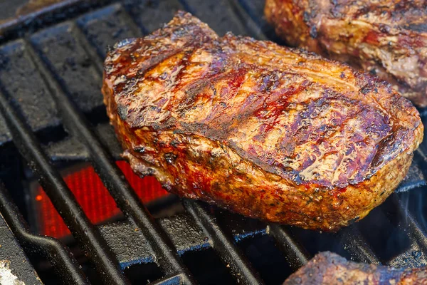 Memanggang steak pada pemanggang gas menyala dan ditembak dengan fokus selektif. Pemanggang halaman belakang. Steak teh. iga-mata steak — Stok Foto