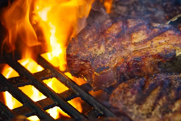 Asar filetes a la parrilla de gas en llamas y disparar con enfoque selectivo. Parrilla del patio trasero. Filete teasty. filetes de costilla — Foto de Stock