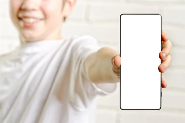 Glücklich lächelnder Junge mit Smartphone-Attrappe vor weißem Hintergrund. leerer Handybildschirm — Stockfoto