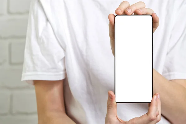 Joyeux garçon souriant montrant la maquette du smartphone dans un fond blanc. écran de téléphone portable vierge — Photo