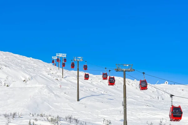 Um teleférico vermelho numa estação de esqui nos Alpes. Gôndola vermelha funicular em uma estância de esqui, sueco, dia ensolarado gelado — Fotografia de Stock