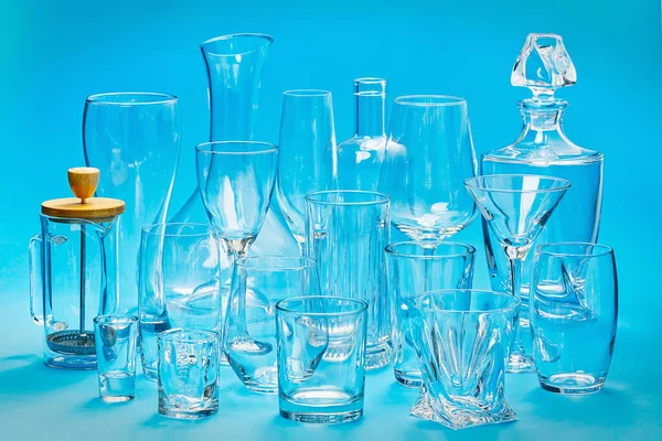 Sada prázdných různých sklenic na modrém pozadí. alkoholické nápoje a koktejly skleněné — Stock fotografie