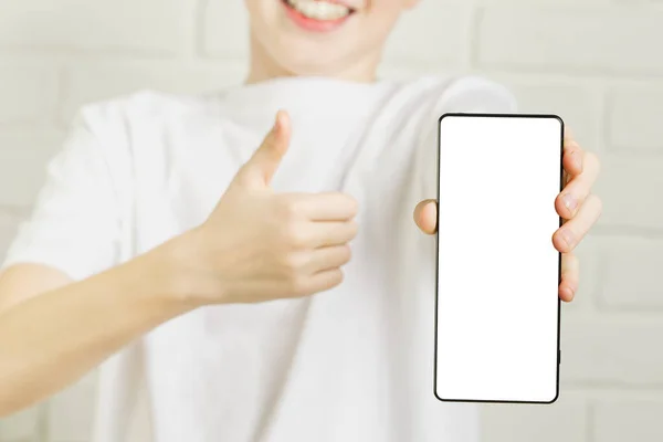 Rapaz sorridente feliz mostrando mockup smartphone em um pano de fundo branco. tela de celular em branco — Fotografia de Stock