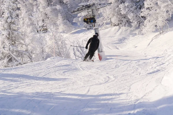 Skifahrer in den Bergen, präparierte Piste und sonniger Tag. Winter-, Freizeit-, Sport- und Personenkonzept — Stockfoto