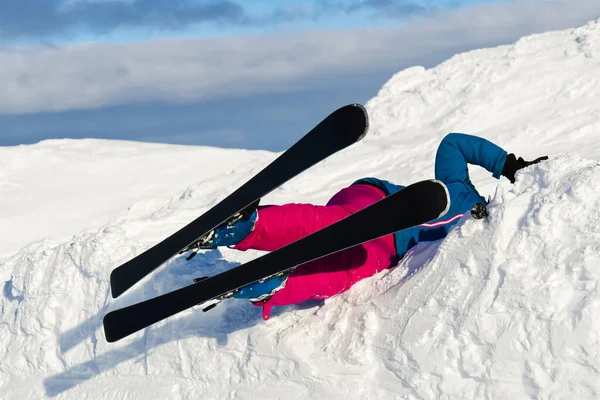 Uma mulher caiu em esquis de uma montanha na neve. atividade de alto risco ou conceito de seguro de esporte extremo — Fotografia de Stock