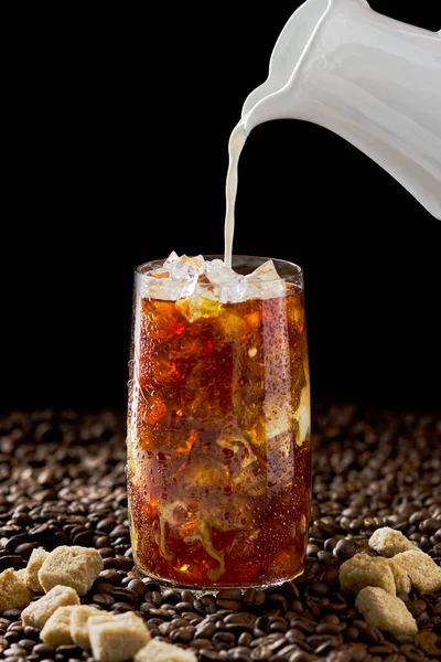 IJskoffie. Lekkere ijskoffie met melk, koude drank in glas met ijs op donkere koffie achtergrond. — Stockfoto