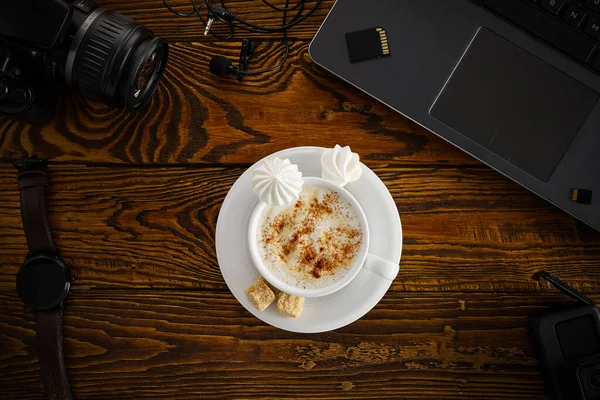 Bekerja dari rumah. meja kantor dengan laptop dan kamera, cangkir kopi di atas meja kayu. Tampilan atas lay rata — Stok Foto