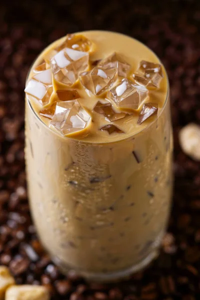 Café helado con leche. Taza de café con leche helada, té con leche sobre fondo de semillas de café oscuro — Foto de Stock