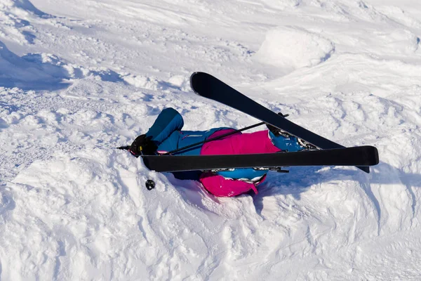 Uma mulher caiu em esquis de uma montanha na neve. atividade de alto risco ou conceito de seguro de esporte extremo — Fotografia de Stock