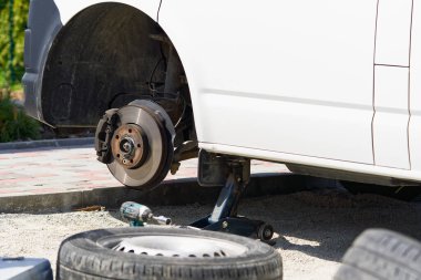 Tamirci araba lastiğini aletle değiştiriyor. Yol yardımı, lastik değiştirme ve onarım, tekerlek.