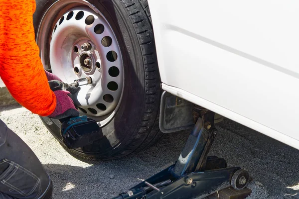 Mechanic changing car tire with tool. road help, changing and repairing tire, wheel.