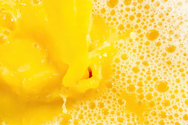 Closeup of splashing orange juice, top view. Splash of fresh sweet orange, mango, fruit juice. Freeze motion of pouring orange juice .