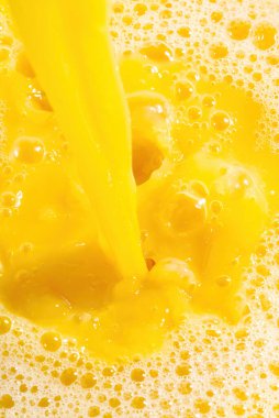 Portakal suyuna yakın çekim, üst manzara. Bir tutam taze portakal, mango, meyve suyu. Portakal suyunun dondurucu hareketi .