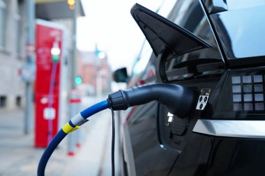 Electromobile charging plug is inserted into vehicle charging socket. electric car at charging station with power outlet, using green energy