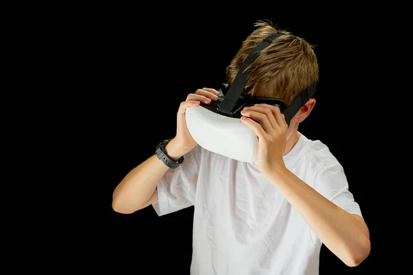 Portrait of young Boy playing VR game in black background. Young hipster wearing VR headset, half body shot. Young generation choose virtual reality, metaverse relaxation concept. remote education