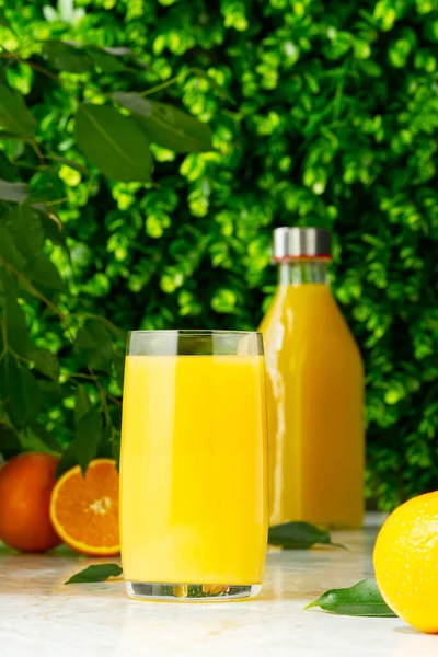 Glass of orange juice and orange juice bottles. Glass and bottle of organic tropical juice