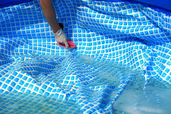 Cleaning pvc inflatable swimming pool, Cleaning the dirty empty pool of algae, The beginning of the swimming season in the hot summer. Cleaning service concept.