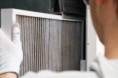Hvac filtresi ev merkezi havalandırma sistemini değiştiriyor. Askerler fırında filtre değiştiriyor. Döner ısı dönüştürücüdeki filtreyi değiştir.